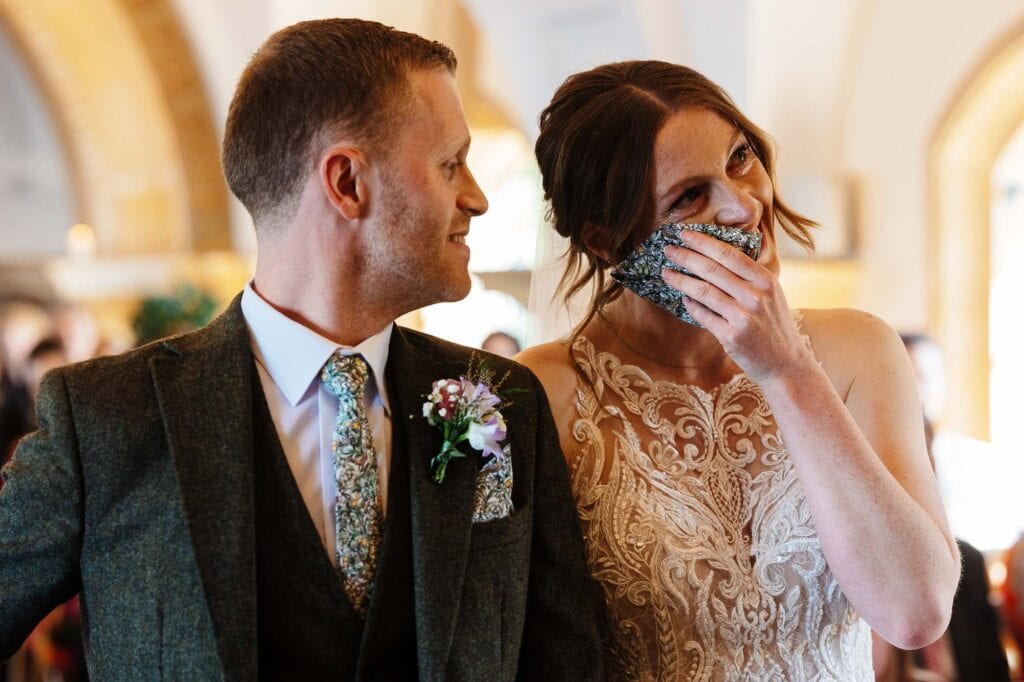 Emotional bride and groom during wedding ceremony, capturing a heartfelt moment with the bride covering her face in joy.