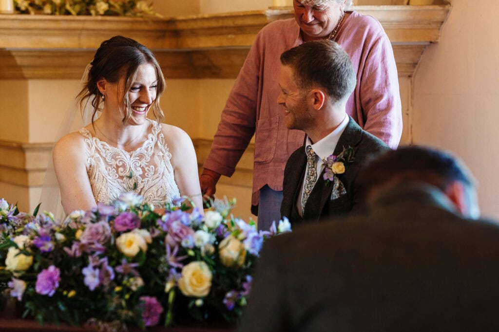 Bride and groom exchanging vows during a wedding ceremony at BGS Weddings, with a joyful atmosphere and floral decorations.