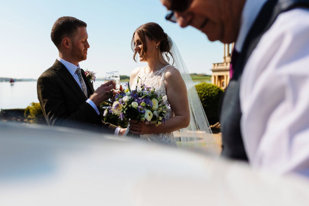 Bride and groom exchanging vows with scenic water views in the background.