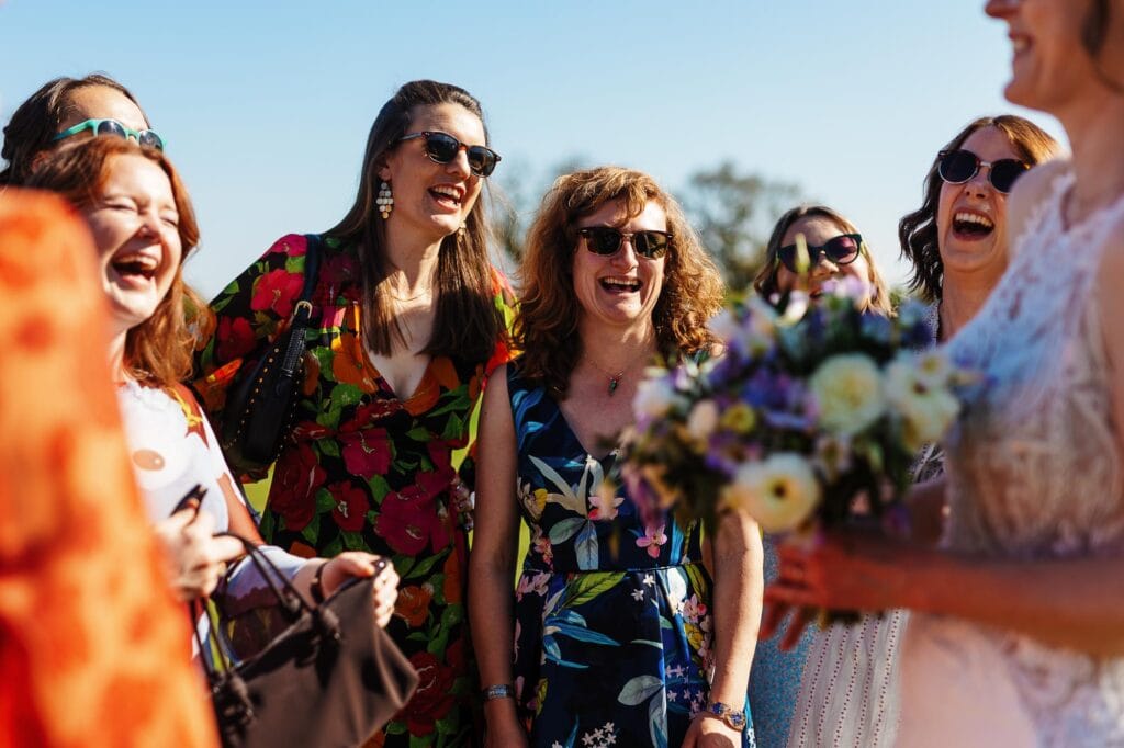 Celebrating a wedding outdoors with happy guests dressed in colourful attire, enjoying the moment and sharing smiles, capturing the joyful atmosphere of a special day.