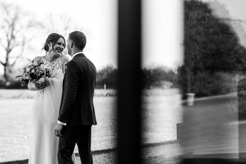 Beautiful black and white image of a bride and groom sharing a special moment during their wedding ceremony in a scenic outdoor setting.