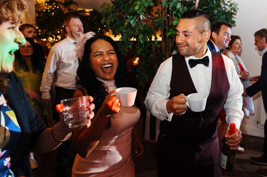 A joyful moment at a wedding reception with guests enjoying drinks and conversation, capturing the lively atmosphere of a wedding celebration.