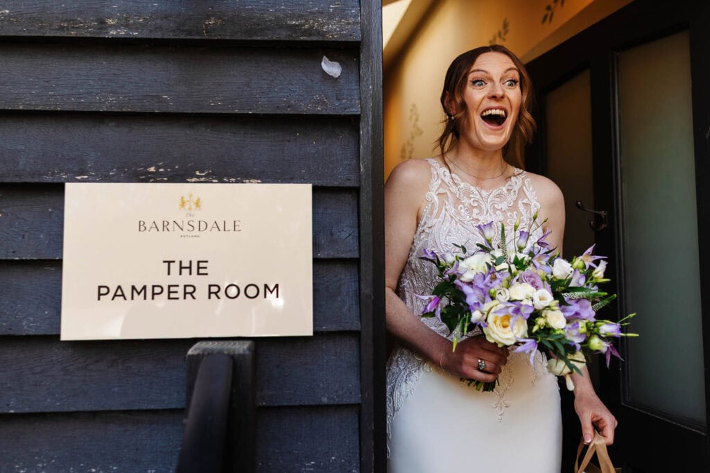 Happy bride holding a bouquet of flowers, smiling joyfully at Barnsdale, ready for her wedding day in the bridal suite.