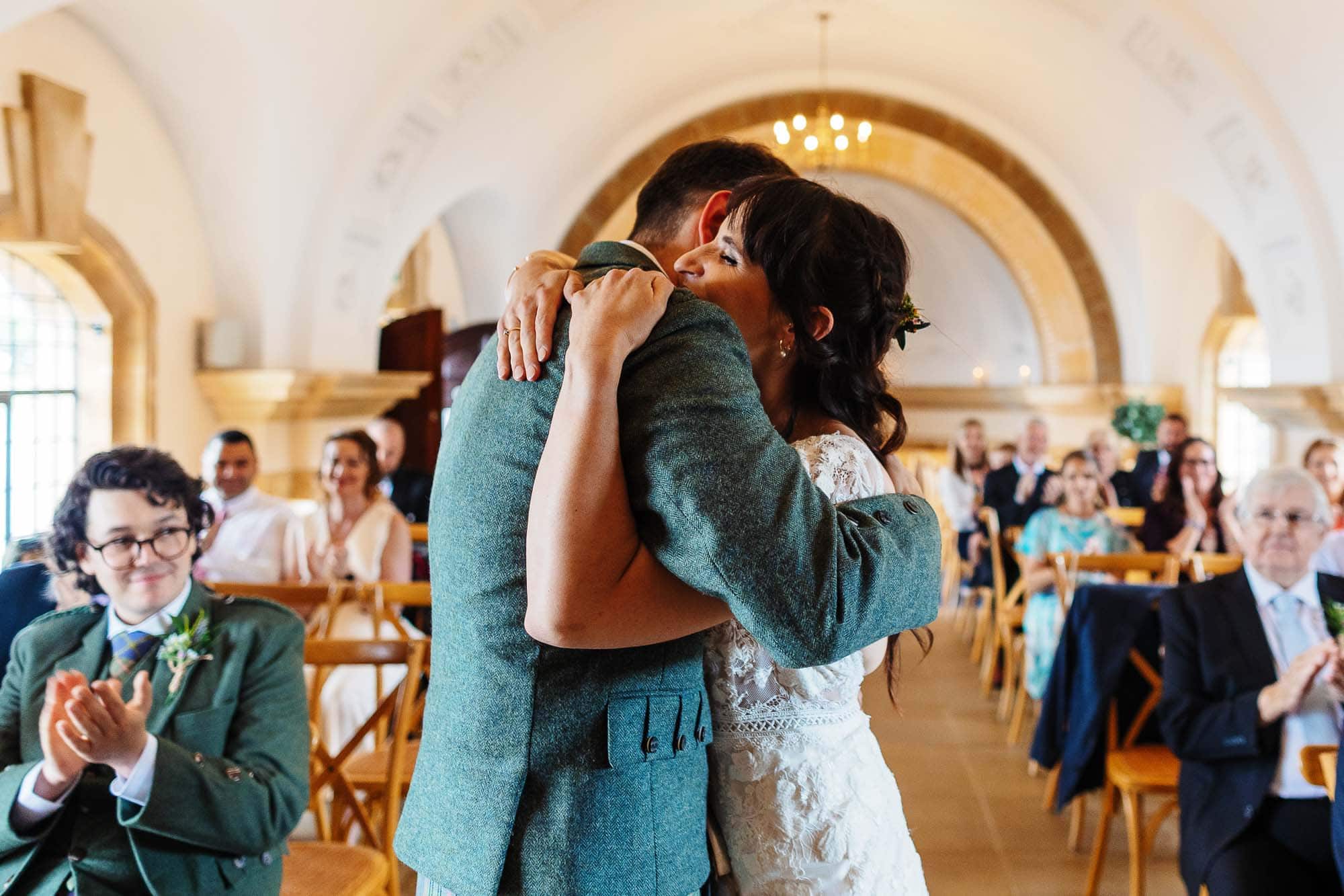 Romantic first dance of a newlywed couple in a beautifully decorated wedding venue with guests watching and clapping.