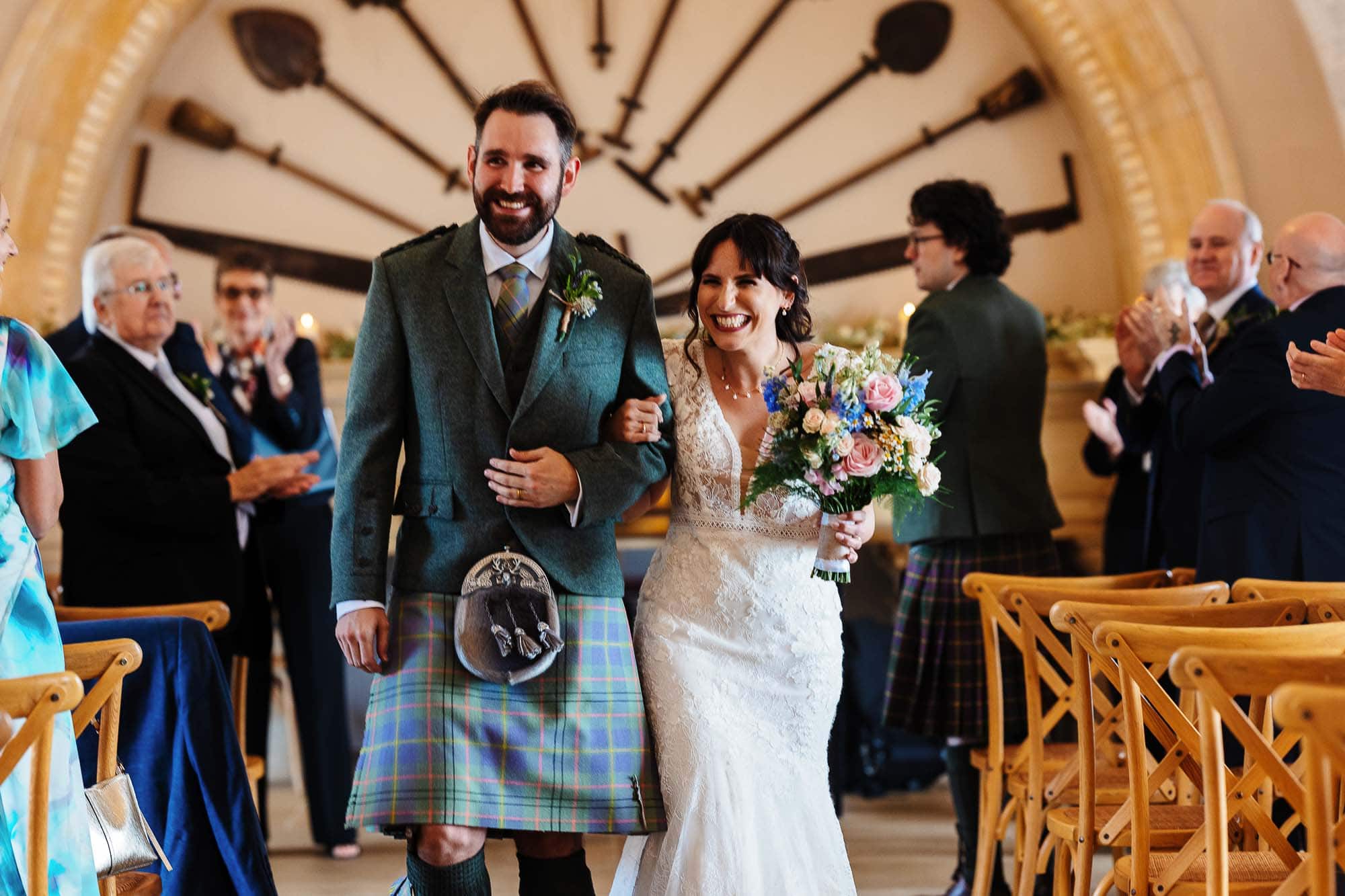 Happy bride and groom walking down the aisle during their wedding ceremony, surrounded by family and friends in a beautiful indoor venue.