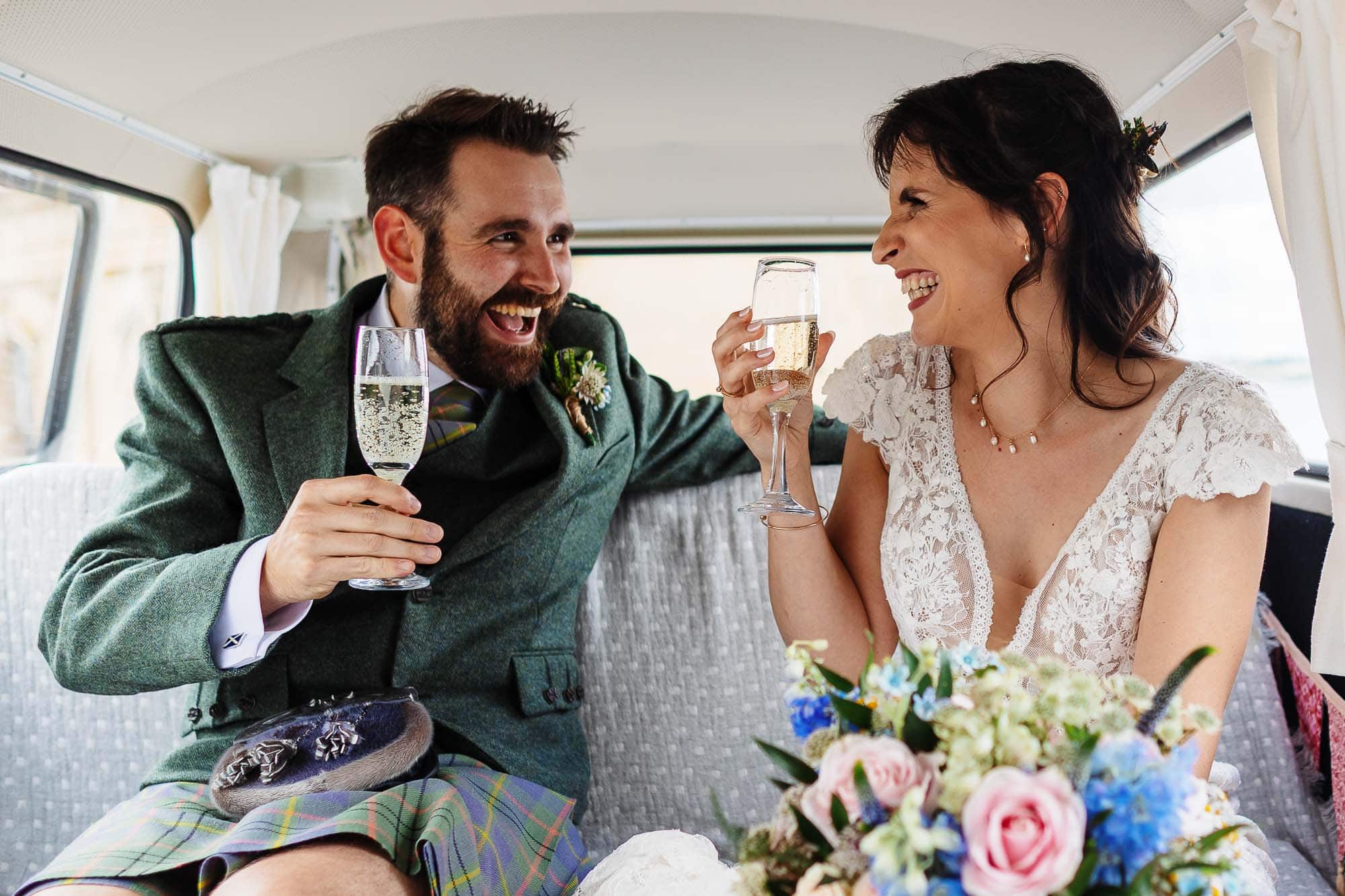 Happy bride and groom toasting with champagne inside a classic wedding car, showcasing their joyful moment on their special day.