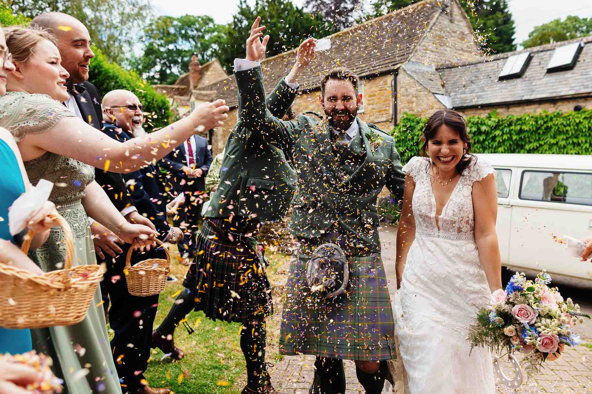 Wedding celebration with confetti and guests, outdoor setting, joyful atmosphere, BGS Weddings.