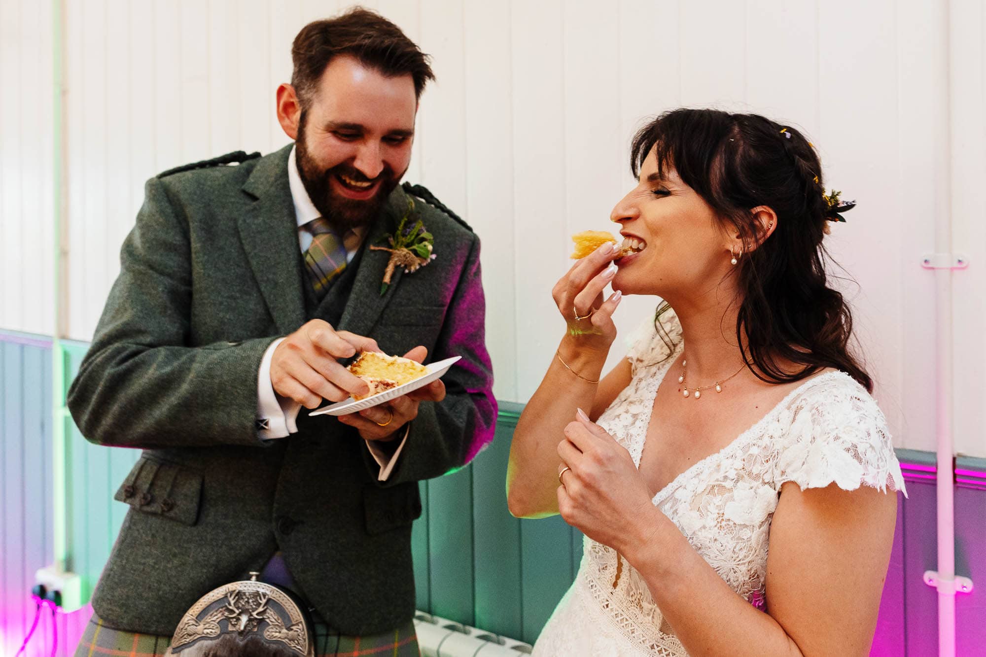 A happy bride and groom sharing a slice of wedding cake during their celebration, showcasing love and joy on their special day.