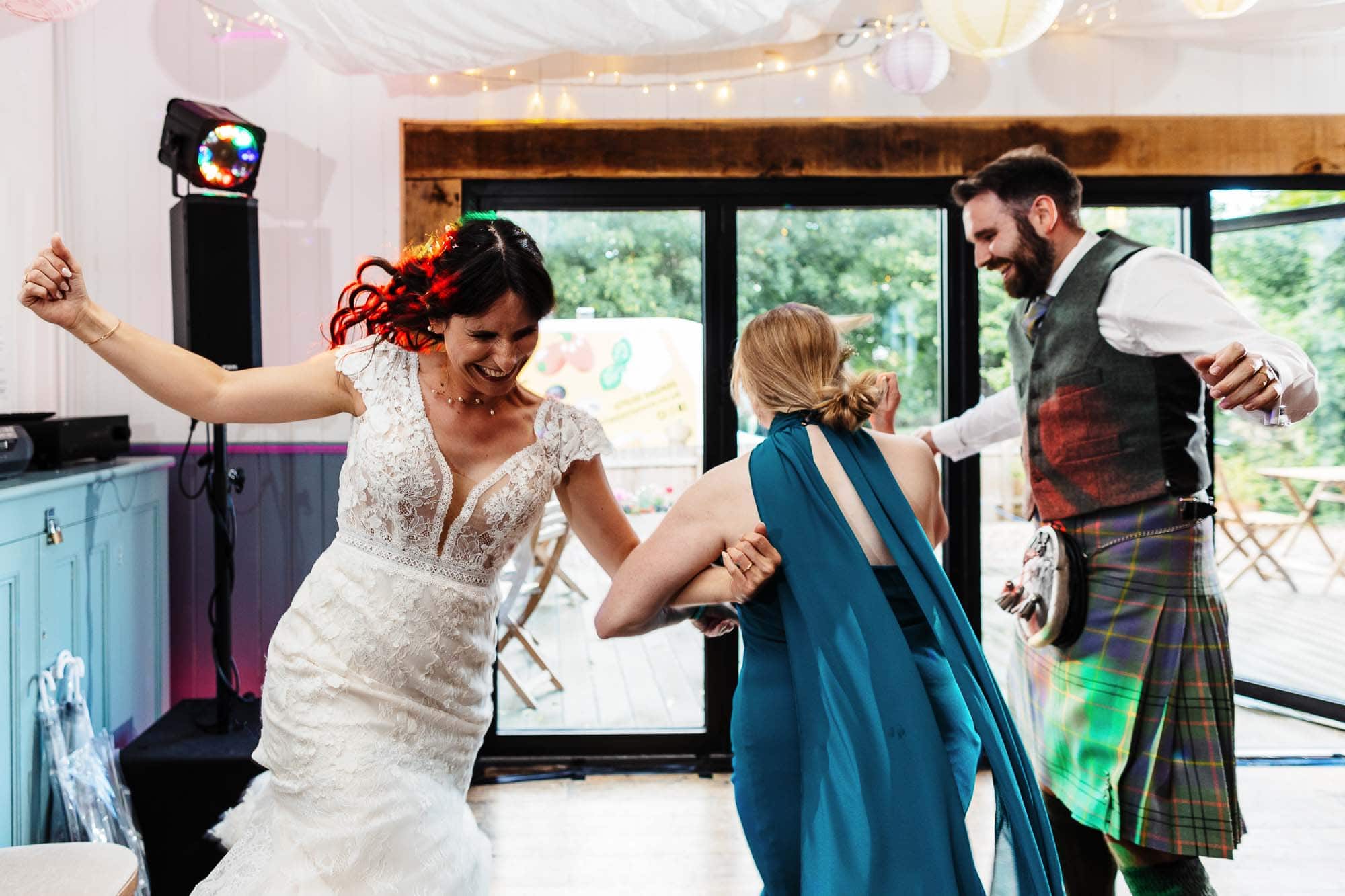 A bride, groom, and guest dancing together during a wedding reception at BGS Weddings, showcasing lively entertainment and a joyful atmosphere.