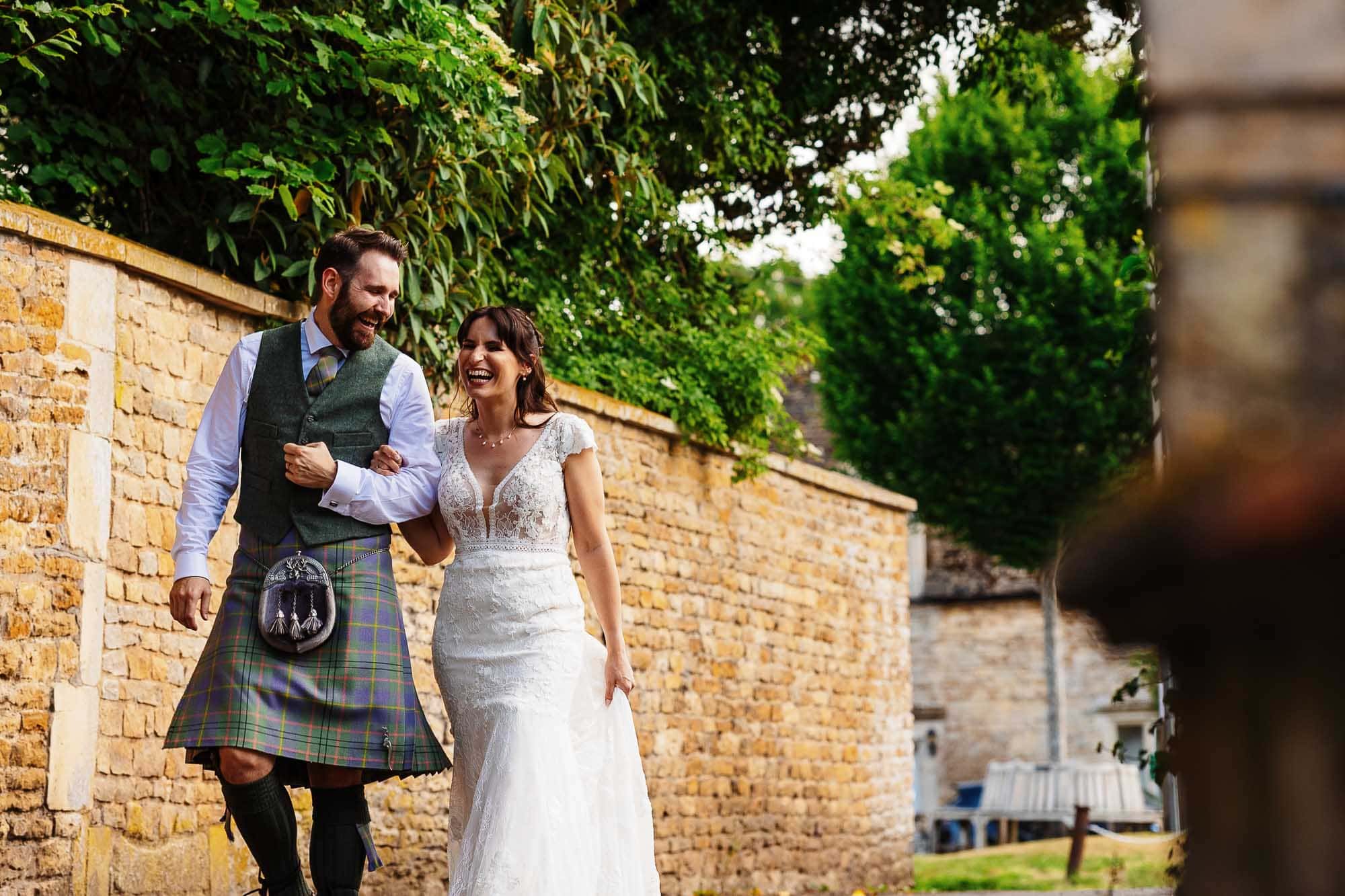 Happy bride and groom walking together in a scenic outdoor setting, showcasing their wedding attire and joyful expressions on their special day.