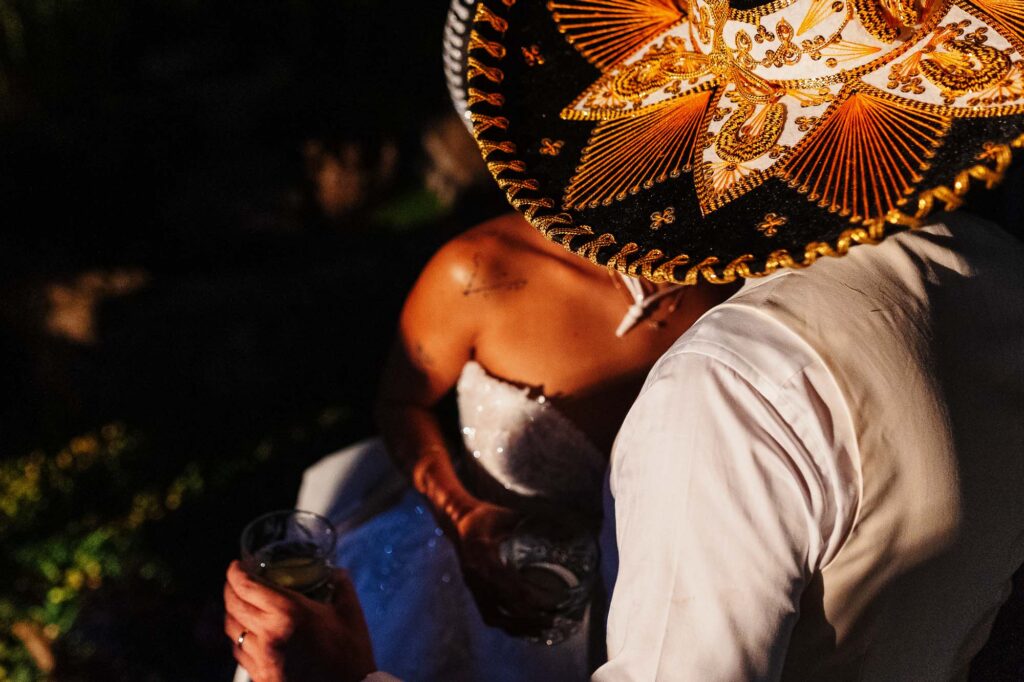 Colorful Mexican wedding celebration with traditional sombrero, bride and groom in festive attire, lively atmosphere, and night setting.